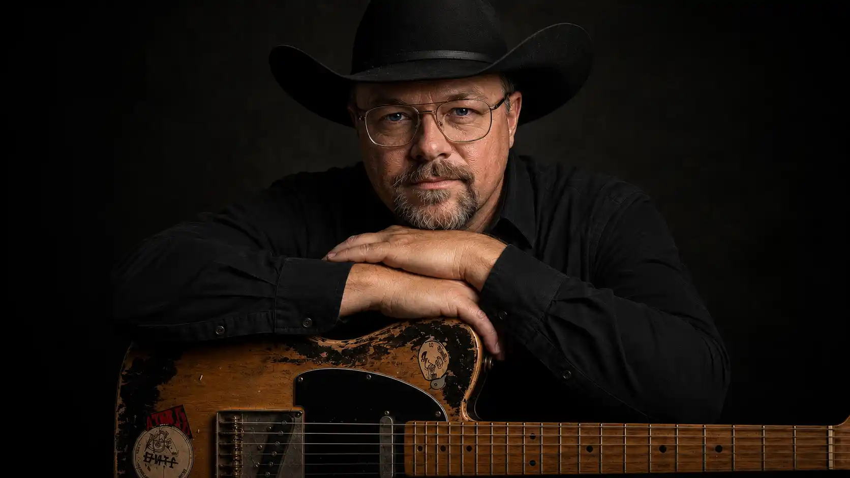 Chad Sanders with his Telecaster guitar in a dark studio, direct gaze